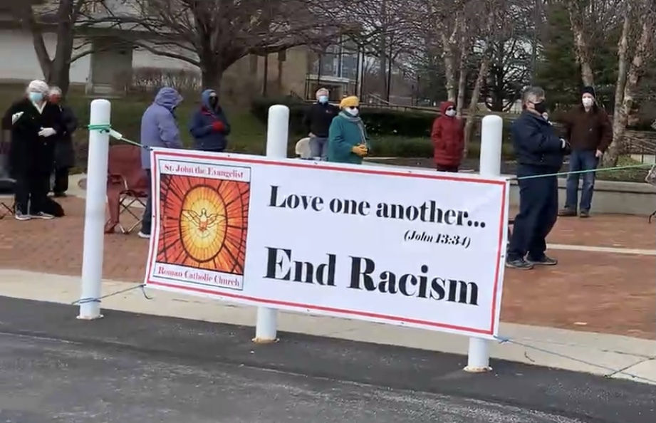 End racism banner at outdoor Mass